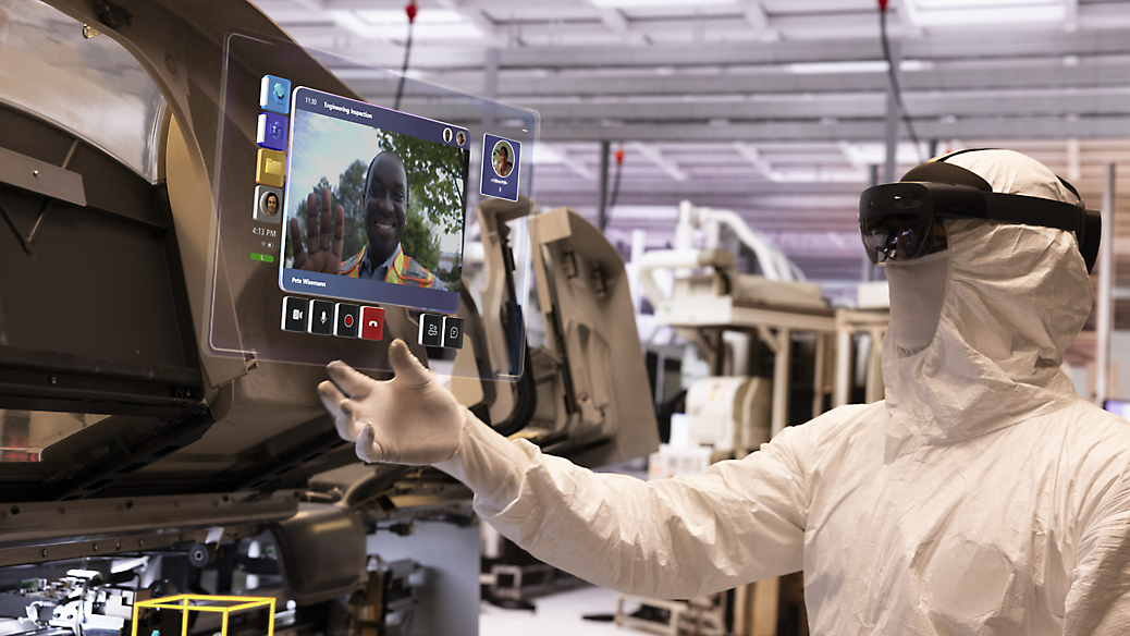 Un técnico con un traje de protección que analiza los datos de una pantalla digital en una fábrica de alta tecnología.