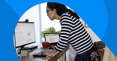 A person standing at their desk and working.