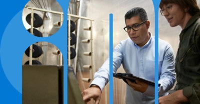 To personer, der ser på et stykke udstyr. En person holder en tablet.