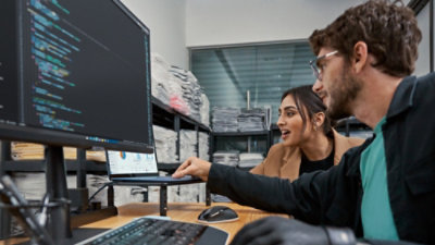 A man and a women looking at a laptop.