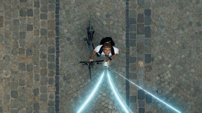 Person with a bike looking up at beams of light