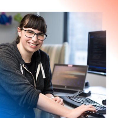 A woman working on her laptop with monitor