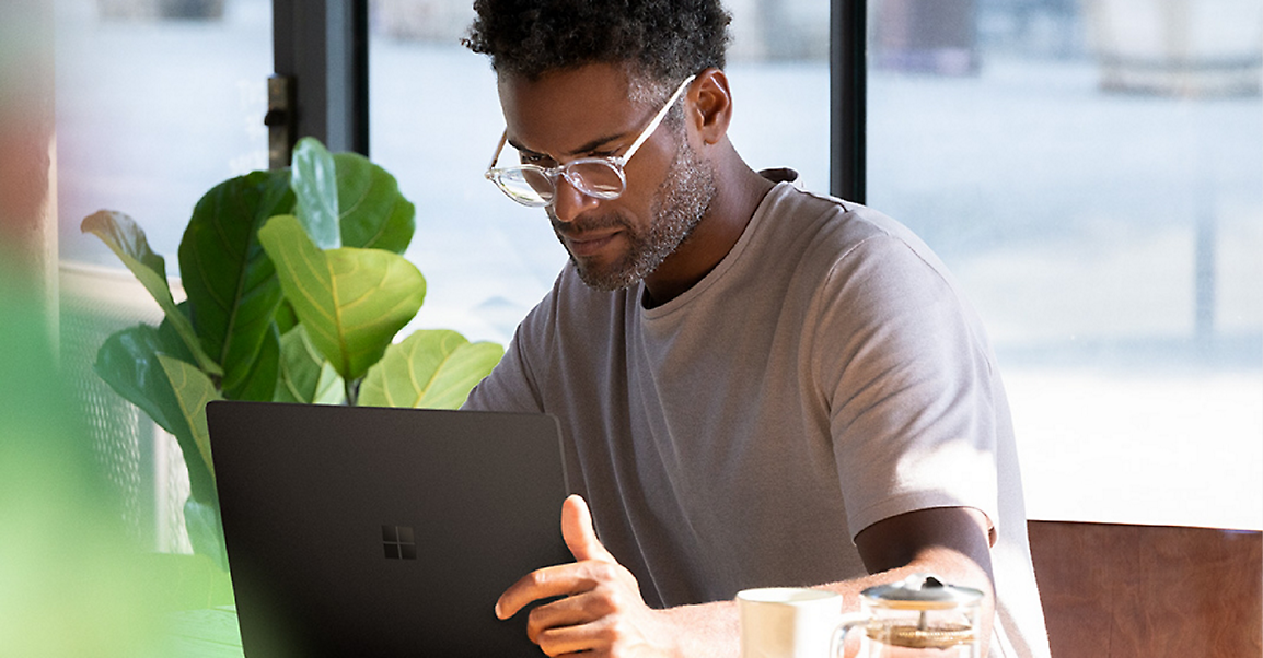  A person seated in a café working on a Surface Book 2