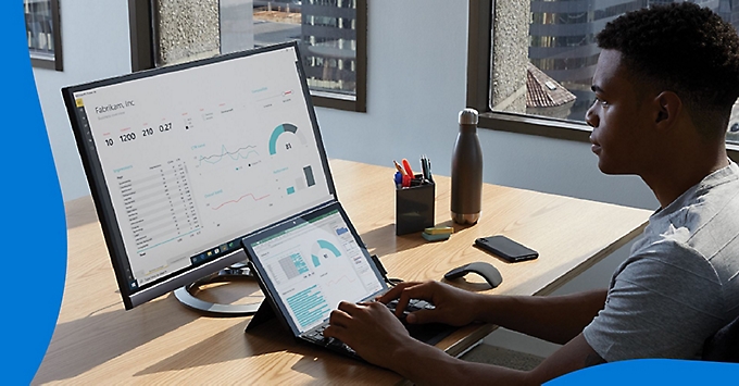 En person som analyserer data som vises på en skjerm på skrivebordet.