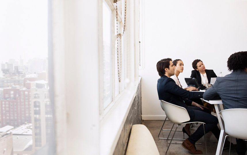 View of several co-workers sitting at a conference table together.