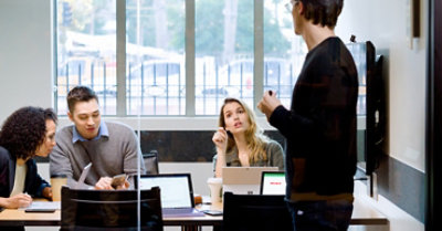 Four people meeting in a conference room with devices open
