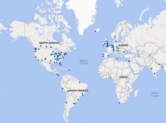 Mapa świata z pinezkami przypiętymi w różnych miejscach na całym świecie.