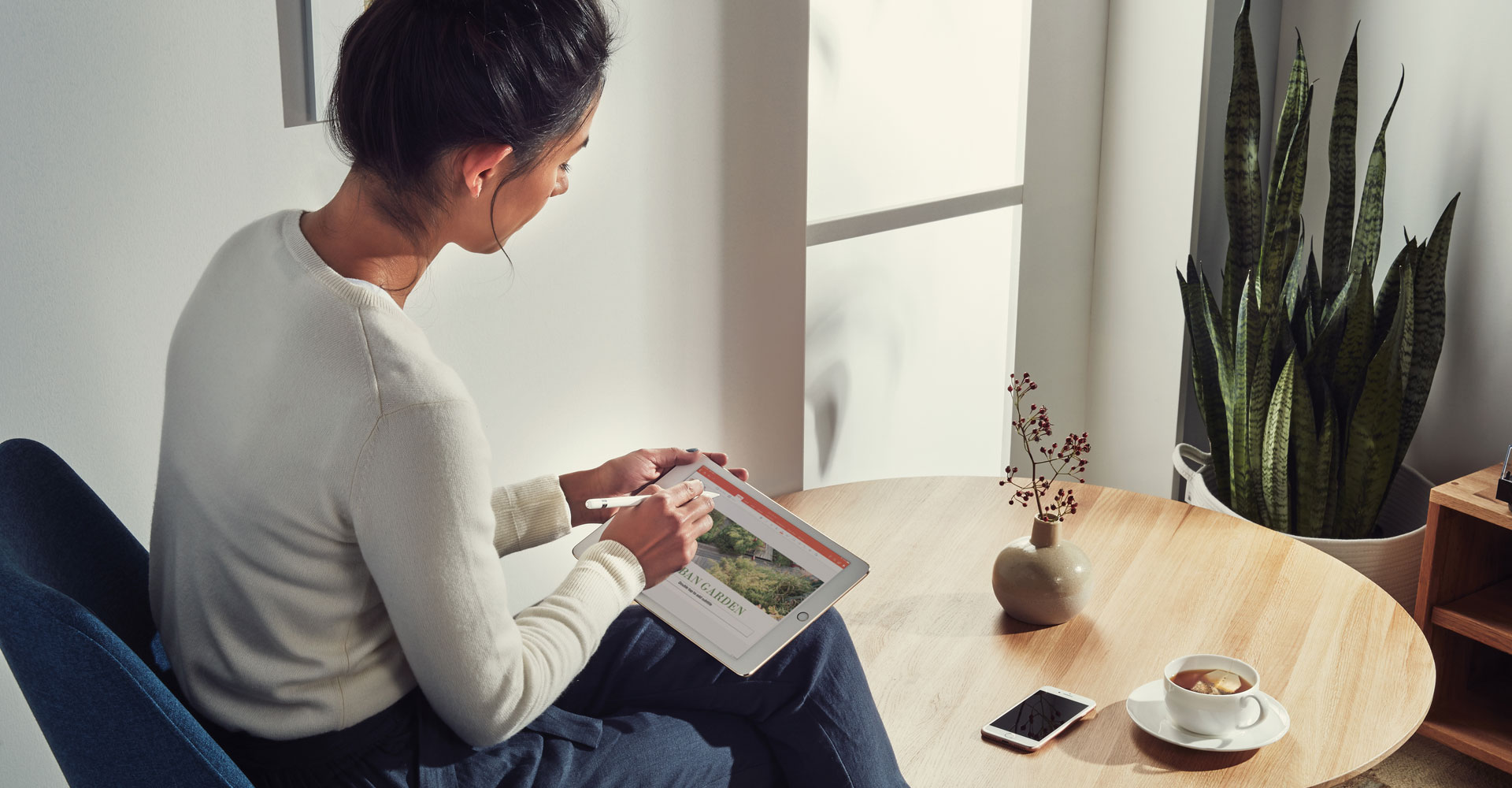 Person using an iPad with a stylus while seated at a table in a casual environment