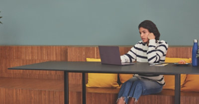 אדם יושב ליד שולחן גדול ומשתמש במחשב נישא