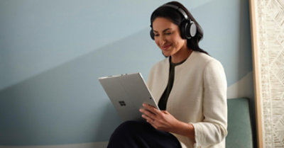 Eine Person, die ohrumschließende Kopfhörer trägt und ein Surface nutzt.