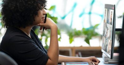 A person participating in a Teams video call on a desktop monitor while using a tablet and pen.