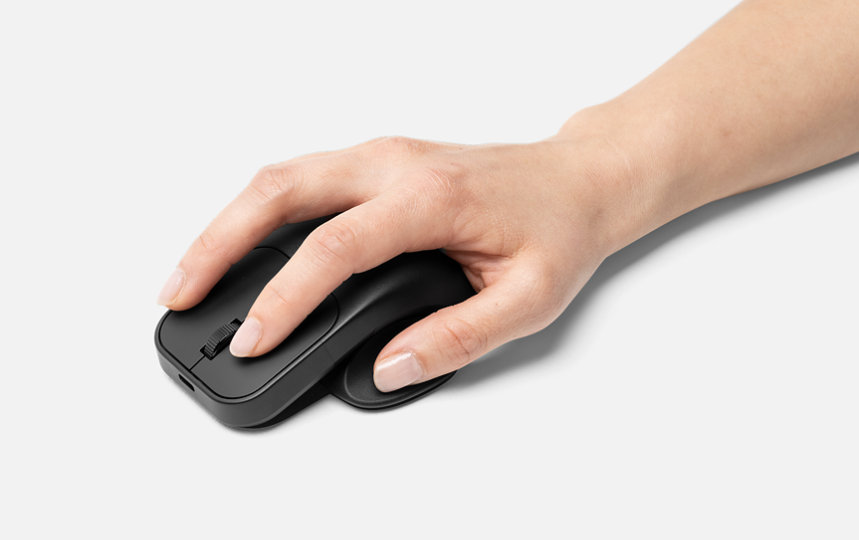 En hånd hviler på Microsoft Adaptive-mus med fastgjort Microsoft Adaptive-musehale og -tommelfingerstøtte. 