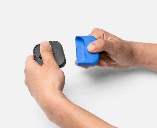 Um par de mãos segura o Rato Adaptável da Microsoft e acopla uma cauda de rato impressa em 3D.
