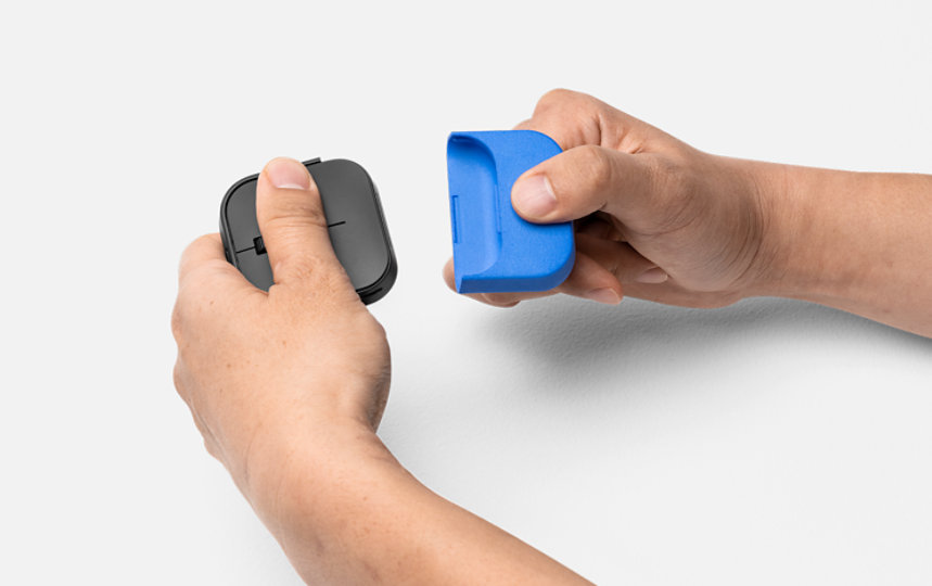 A pair of hands holds Microsoft Adaptive Mouse and attaches a 3D printed mouse tail.