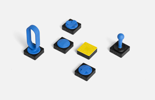 An overhead view of the Microsoft Adaptive Button and a variety of 3D printed button toppers.