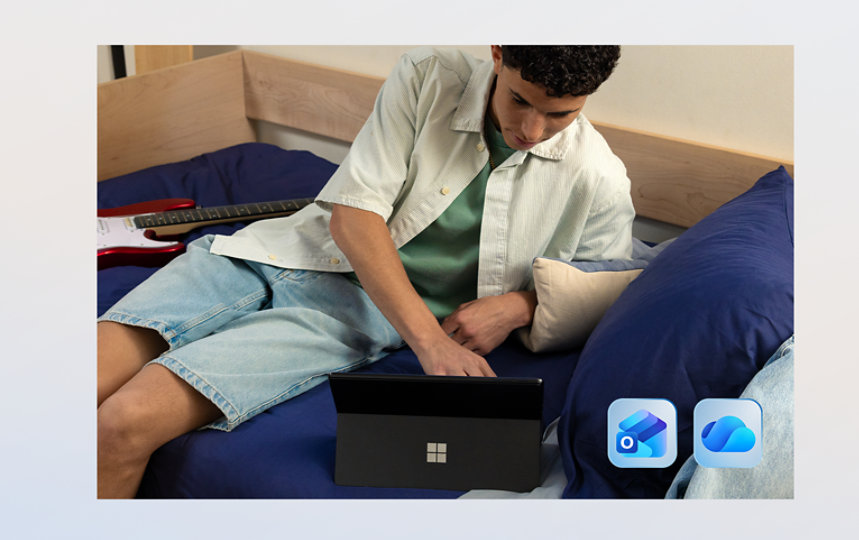 Egy fiatal férfi egy Surface Pro eszközt használ az ágyán, az alján látható két Microsoft 365-alkalmazással, például: Outlook és OneDrive. 