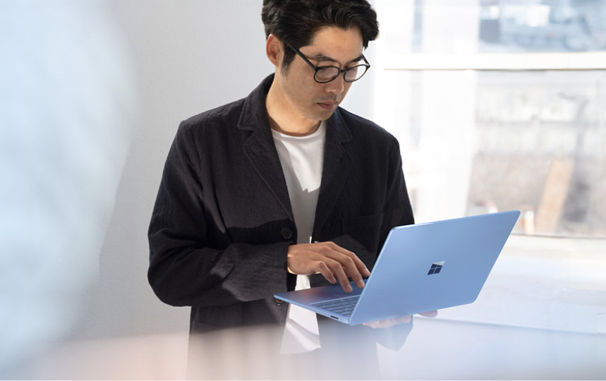 サファイア色のSurface Laptop Copilot plus PCを使っている男性。