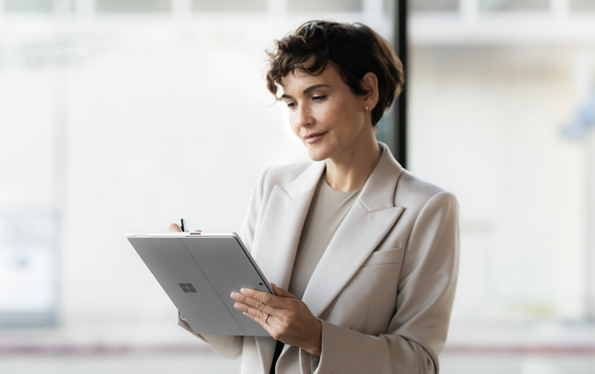 Surface Pro 10のタッチスクリーンにSurface Penで書き込むビジネススーツ姿の人。