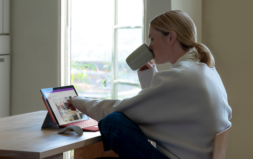自宅で作業しているユーザーが、Surface Pro のタッチ操作を使用して OneNote ドキュメントを編集している。