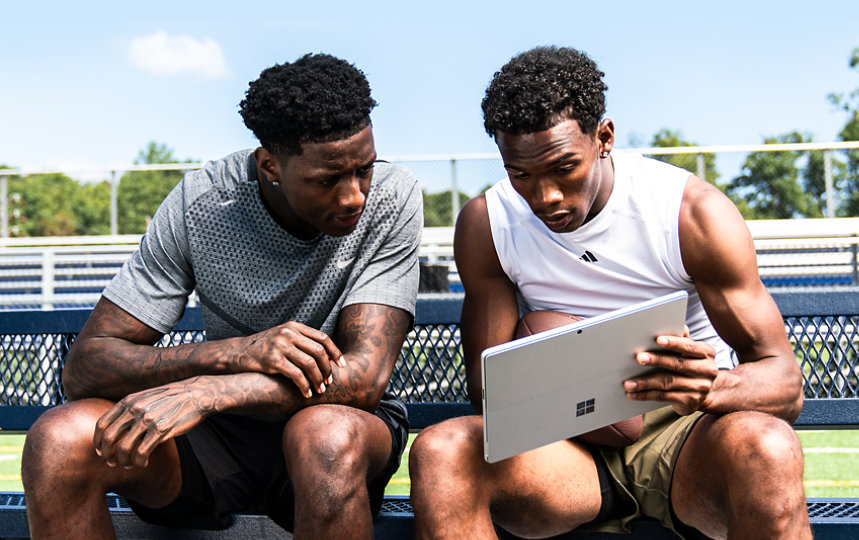 Garett Wilson holds a Surface Pro 9 tablet while Sauce Gardner looks over his shoulder.