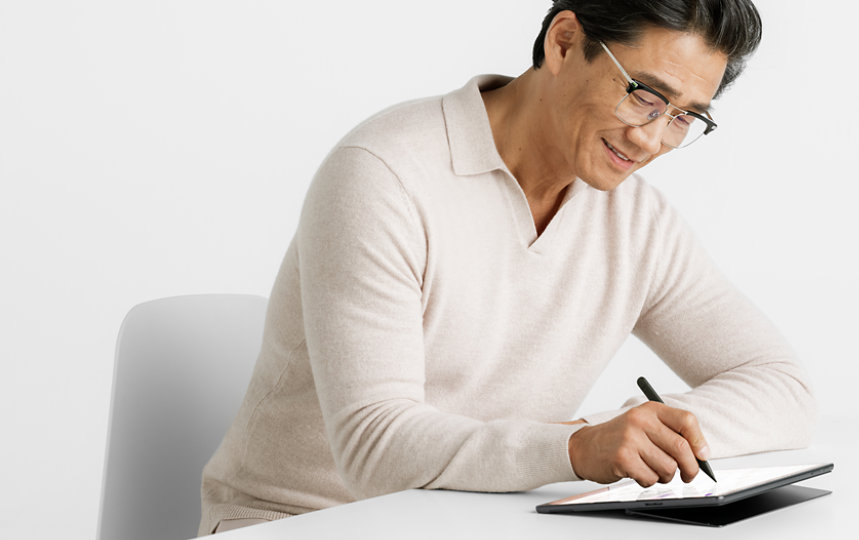 A person uses a Surface Slim Pen for Business to write on the screen of a device.