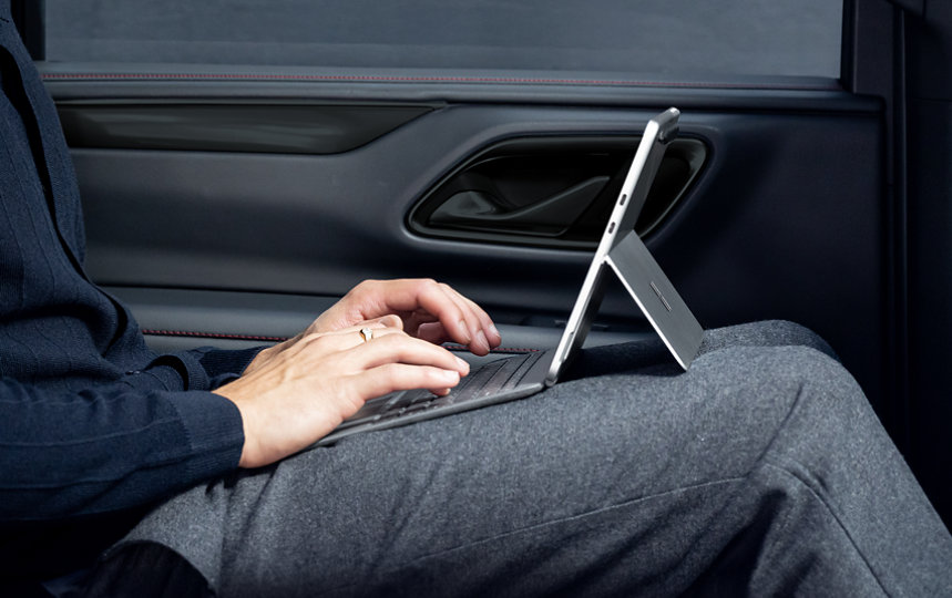 A person sits in a car while typing on Surface Pro 12-inch Keyboard connected to a Surface Pro. 