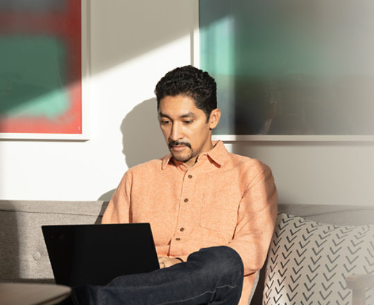 Osoba korzystająca z Microsoft 365 na laptopie w strefie wypoczynkowej.