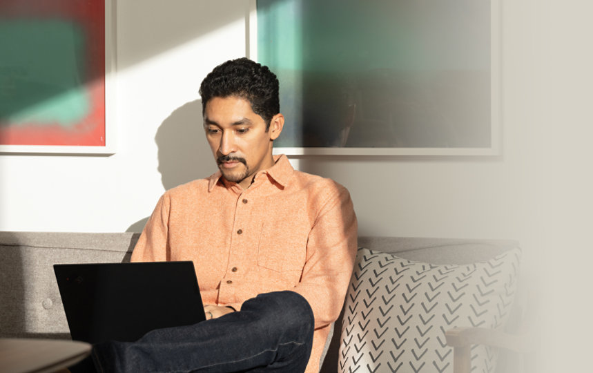 A man using Microsoft 365 with a laptop in a lounge area.