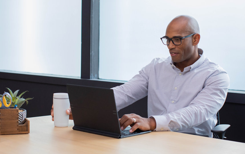 Um homem atento trabalha em seu notebook em um escritório.