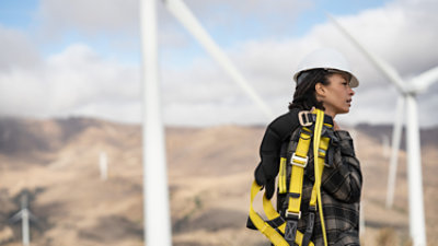 Eine Frau steht vor einem Windpark und ist bereit für die Arbeit.