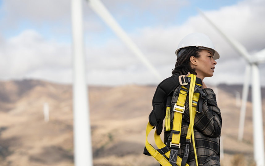 A woman standing in front of a wind farm, ready to work.