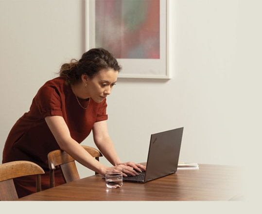 Kobieta korzystająca z Microsoft 365 z laptopem na stole w sali konferencyjnej.