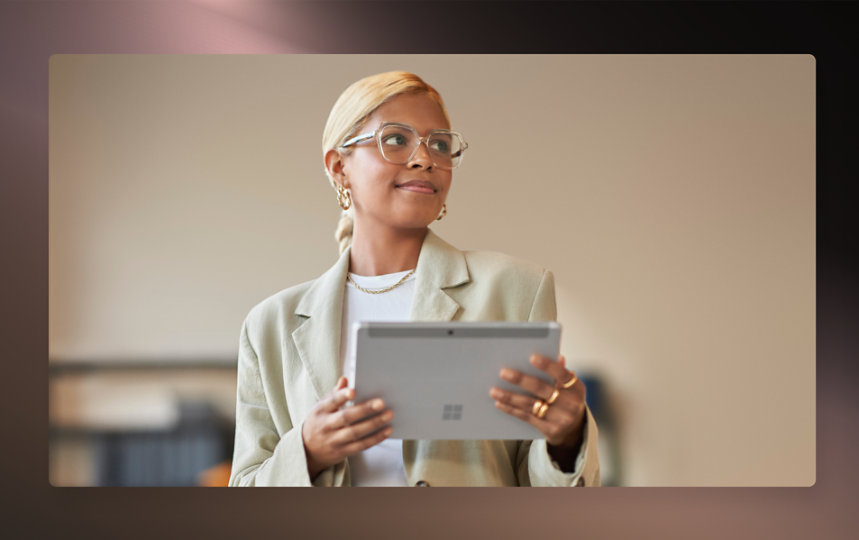 Business attired woman holding a two in one device in an office.