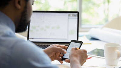 Una persona che utilizza un cellulare alla scrivania