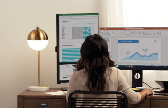 Una persona sentada ante un escritorio con varios monitores de escritorio.