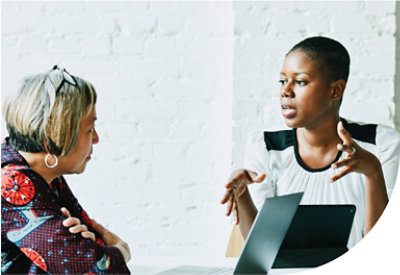 Două persoane care poartă o discuție în fața unui laptop.