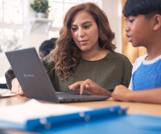 Photo of woman and young boy looking at laptop together