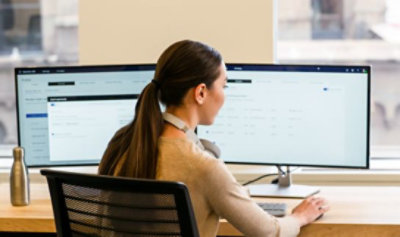 A person is sitting on the chair and working with multiple monitors