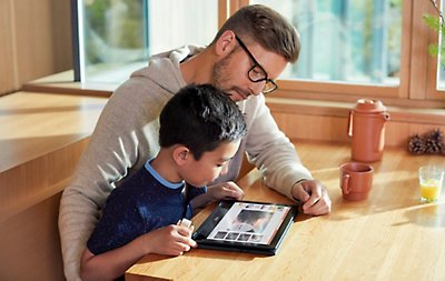 A parent and child using a tablet to look at a PowerPoint presentation.