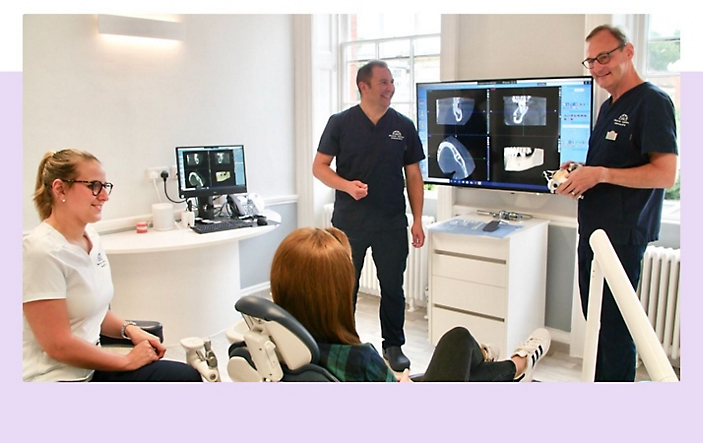 Tři dentální specialisté, kteří s pacientem probírají rentgenové snímky