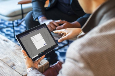 A person holding a tablet that is displaying Tasks in Teams and the ability to select different teams to publish a task to.