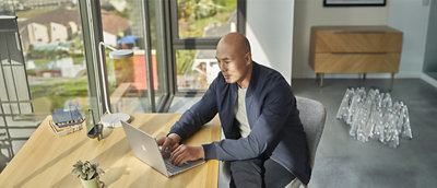 A man sitting at a table using a laptop.