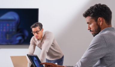 Two people working on laptops in a conference room
