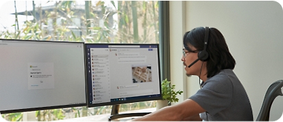 Egy férfi egy íróasztalnál ül, ahol két monitorral és mobileszközökkel dolgozik távolról az otthoni irodájában