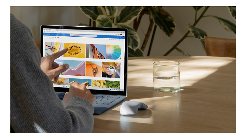 Una persona usando un dispositivo de pantalla táctil para ver imágenes en OneDrive.