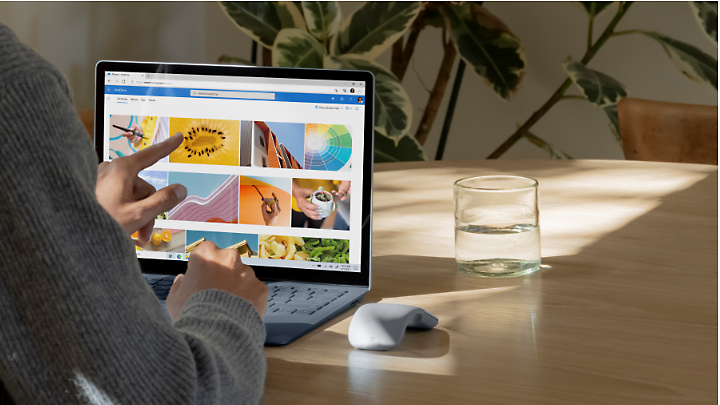 A person using a touchscreen device to look through images on OneDrive.