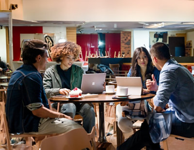 A group of people sitting around a table with laptops.
