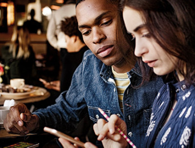 Two people sitting at a café table using a mobile device