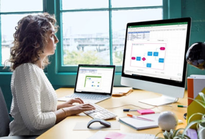 Una persona usa una portátil y un monitor de escritorio grande para trabajar en Visio.