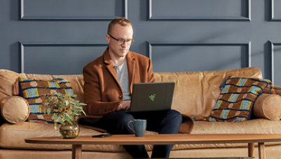 Person seated on a couch in front of a coffee table using a laptop.